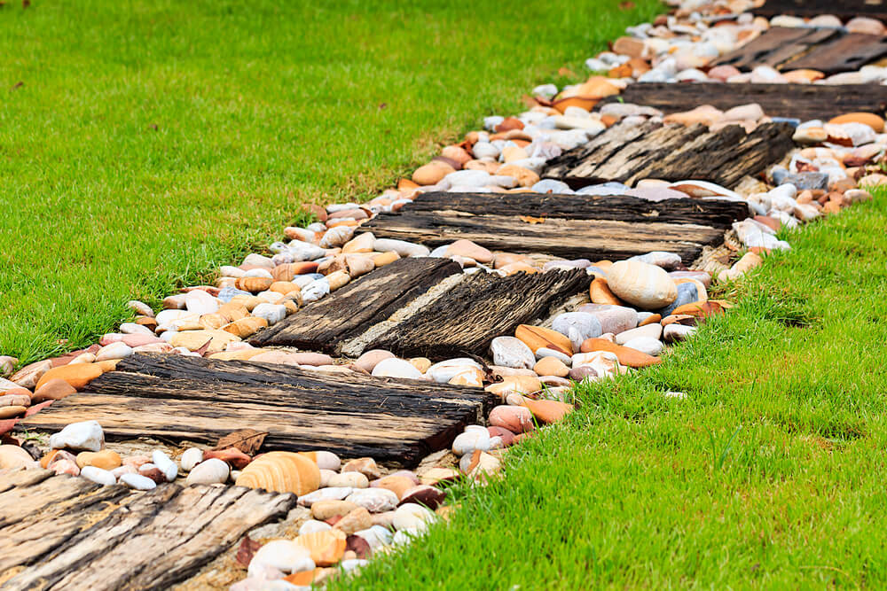 Çimenlerin ortasında taşlarla süslenmiş tahtadan patika