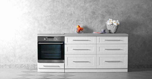 gri duvar önünde bayz çekmeceli dolaplar ve beyaz çekmeceli siyah fırın