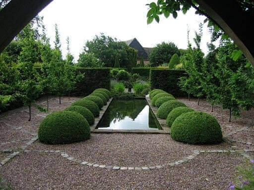 Ağaçlar yuvarlak ve kare çalılarla etrafı sarılı dikdörtgen bahçe göleti