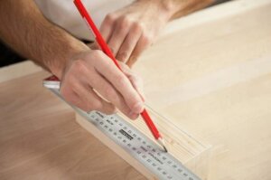 Tahta bir takozun üzerinde cetvel ve kalem yardımıyla ölçüm yapılıyor